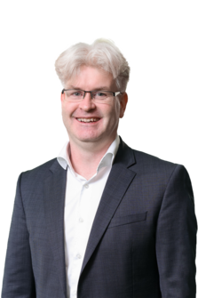 Christian Knell im Anzug und in die Kamera lächelnd.