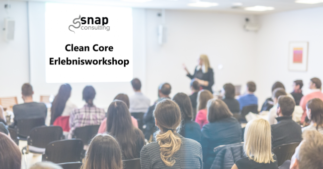 Ein Vortragsraum mit vollem Publikum, vorne eine Vortragende. Auf der Präsentation steht "Clean Core Erlebnisworkshop"