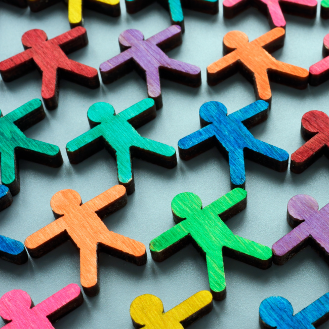 viele kleine bunte Strichmännchen aus Holz, sie halten sich an den Händen.