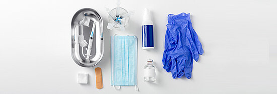 Foto, das eine Nahaufnahme von Spritzen, Handschuhen, Masken und anderen medizinischen Geräten zeigt.