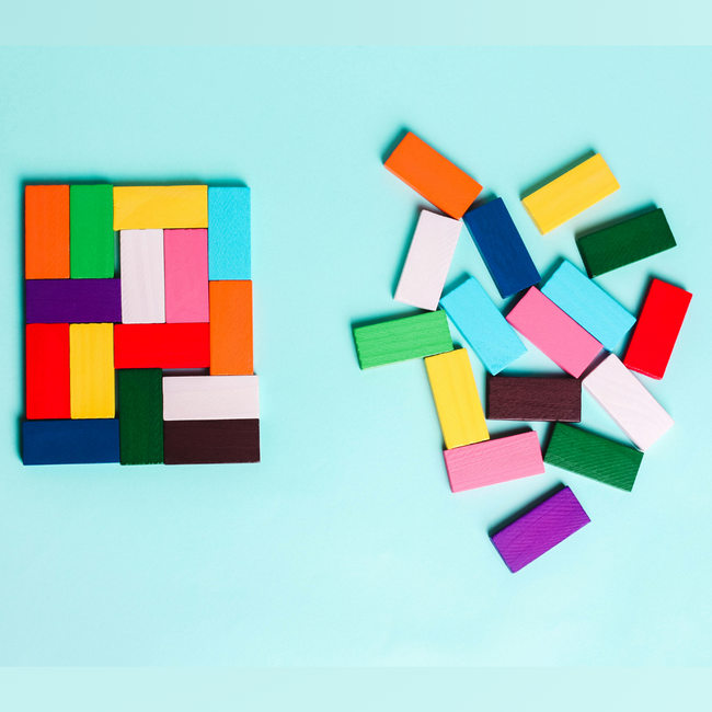 auf einem hellblauen Hintergrund liegen zwei Haufen bunte Blöcke. Der Linke ist geordnet und sortiert und der Rechte ist durcheinander und chaotisch.