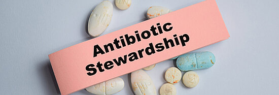 Foto, das ein Post-It mit der Aufschrift "Antibiotic Stewardship" (Antibiotika-Verwaltung) zeigt, welches auf mehreren Pillen liegt.