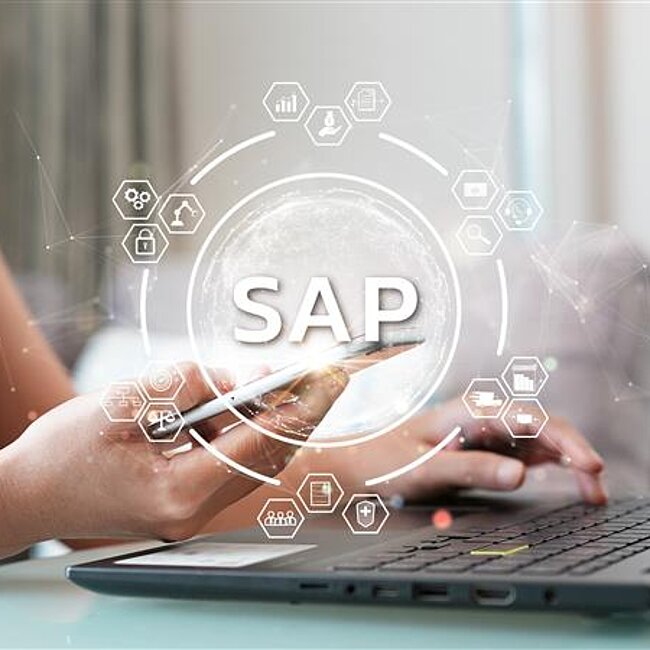 eine Person die mit der linken Hand auf einer Laptoptastatur tippt und mit der anderen Hand ein Smartphone hält. Ein großer Schriftzug liest "SAP"