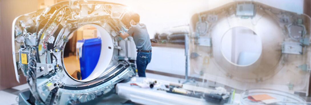 Foto, das einen Instandhaltungstechniker zeigt, der in einem Krankenhaus eine CT-Scanner-Maschine wartet.